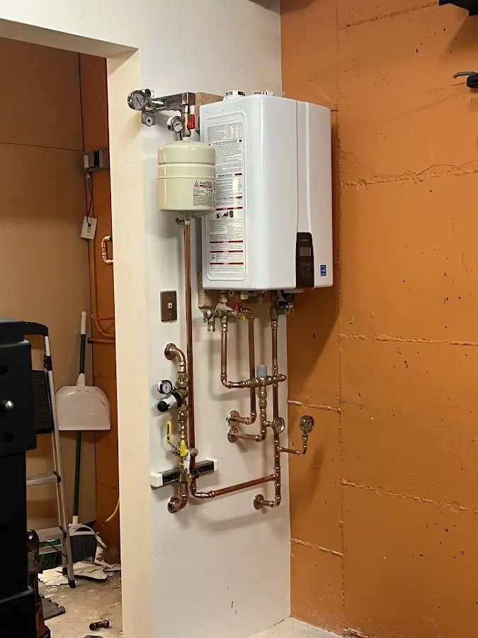 Plumbing technician inspecting water heater connections in Mack